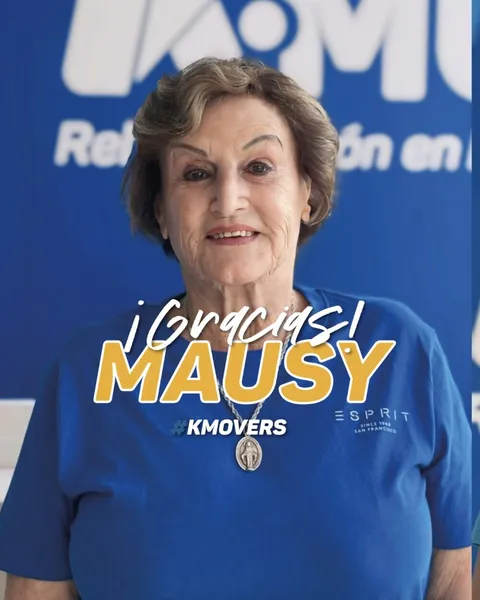 ¡Gracias, Mausy! #KMOVERS: Mausy con polera azul frente al logo de KMOVE