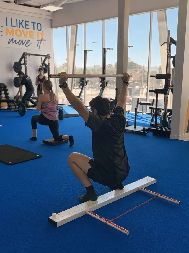 Kmover haciendo sentadilla overhead sobre una tabla