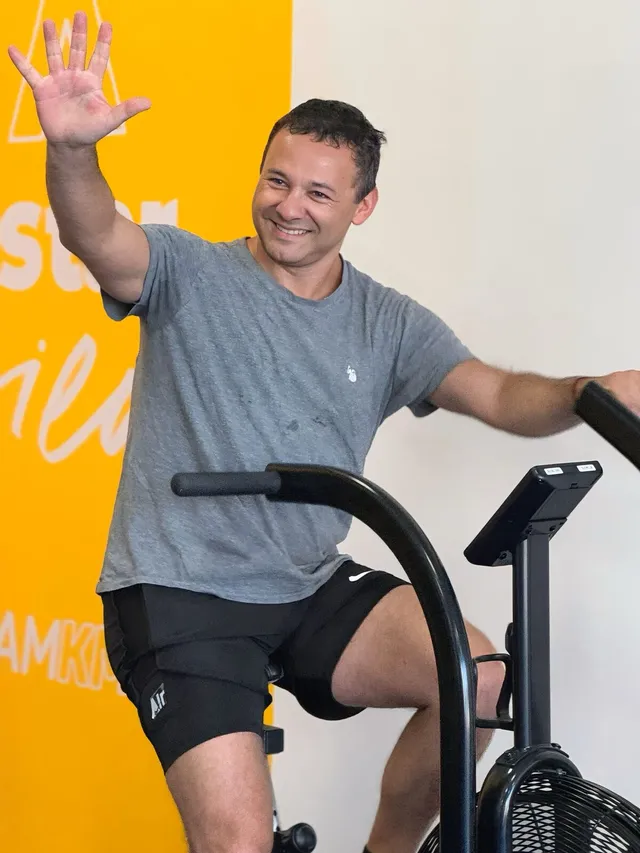 Kmover saludando mientras entrena en bicicleta de aire