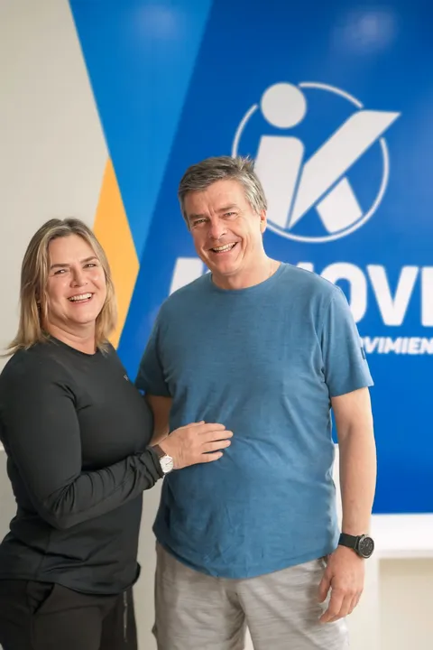 Pareja de kmovers sonriendo frente al logo de KMOVE